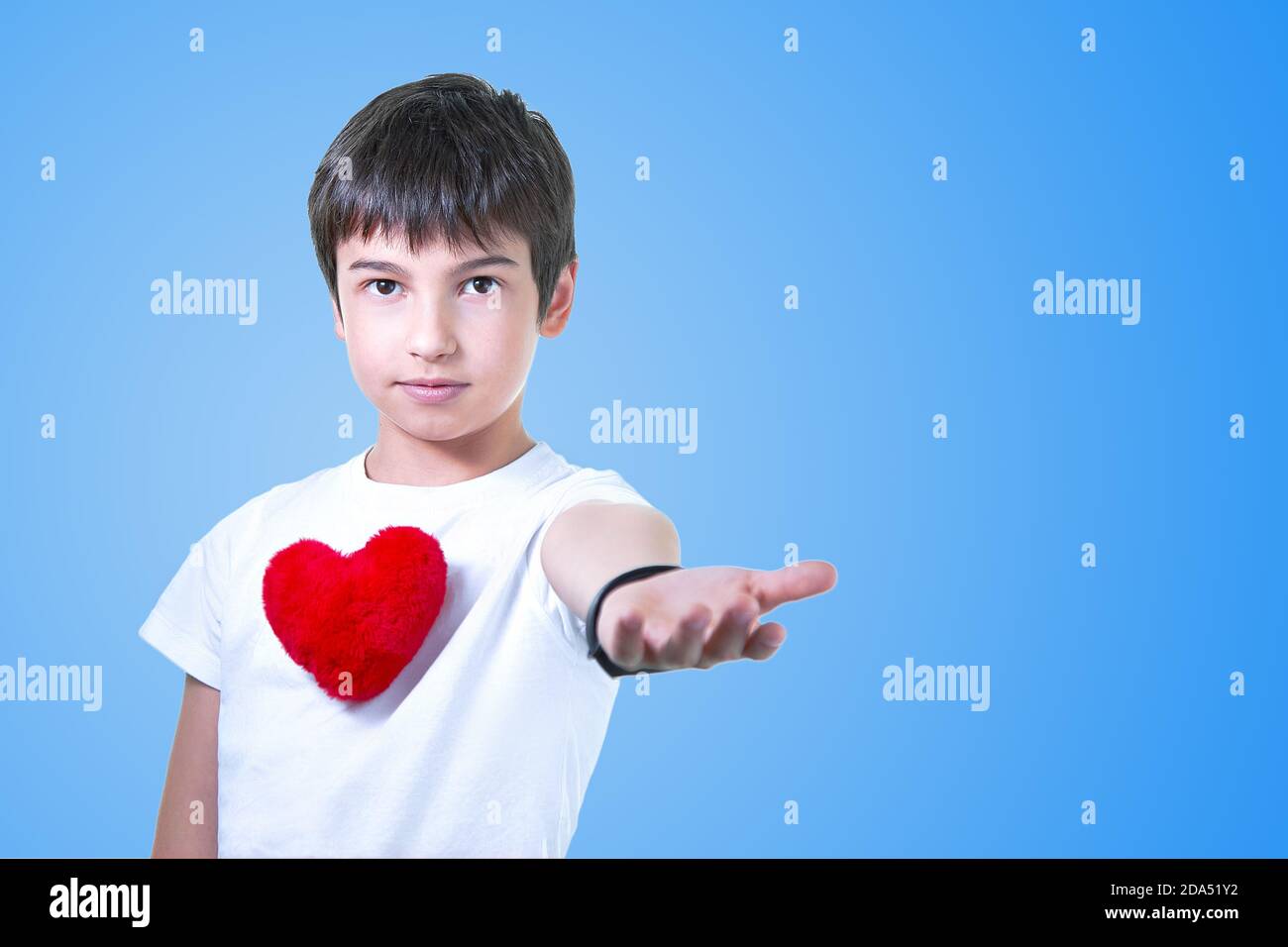 Joli garçon d'école dans une chemise légère isolée sur bleu. Avec un grand coeur Banque D'Images