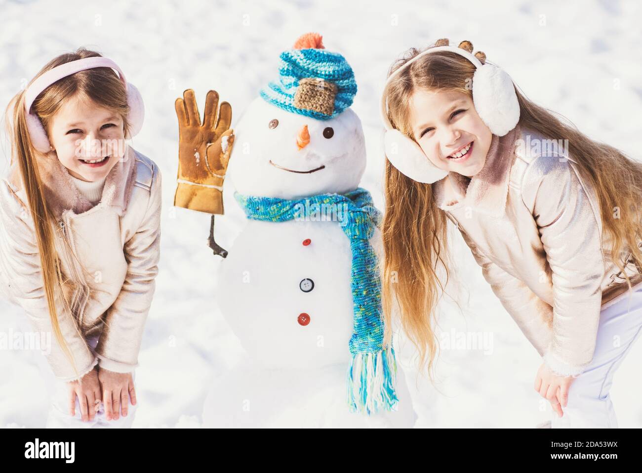 Les enfants font du bonhomme de neige sur fond de neige blanc. Thème Noël vacances hiver nouvel an. Banque D'Images
