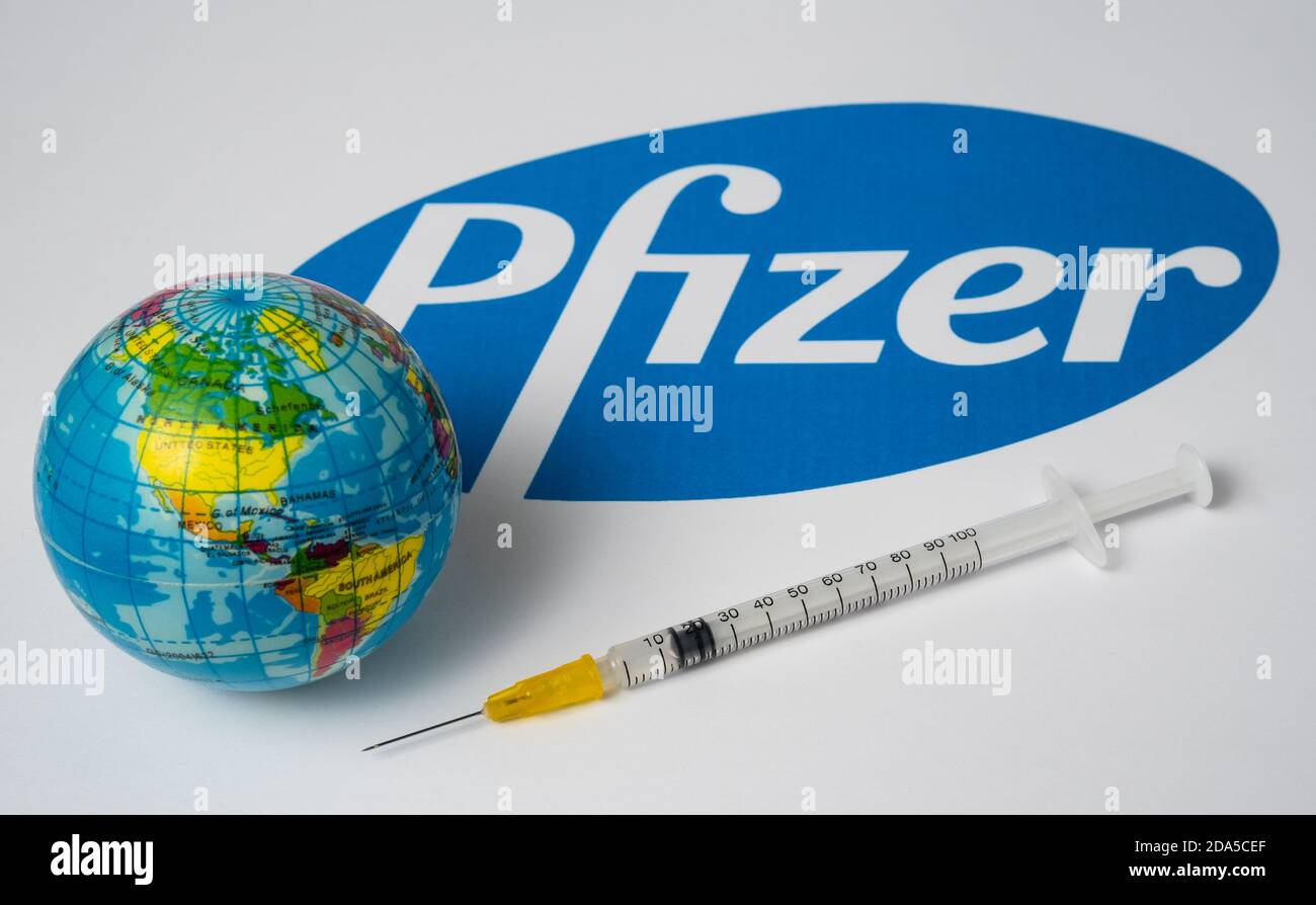 Stafford / Royaume-Uni - novembre 9 2020 : concept de vaccin Covid-19 de Pfizer. Seringue et un globe-jouet flou avec logo de la société Pfizer flou sur le Banque D'Images