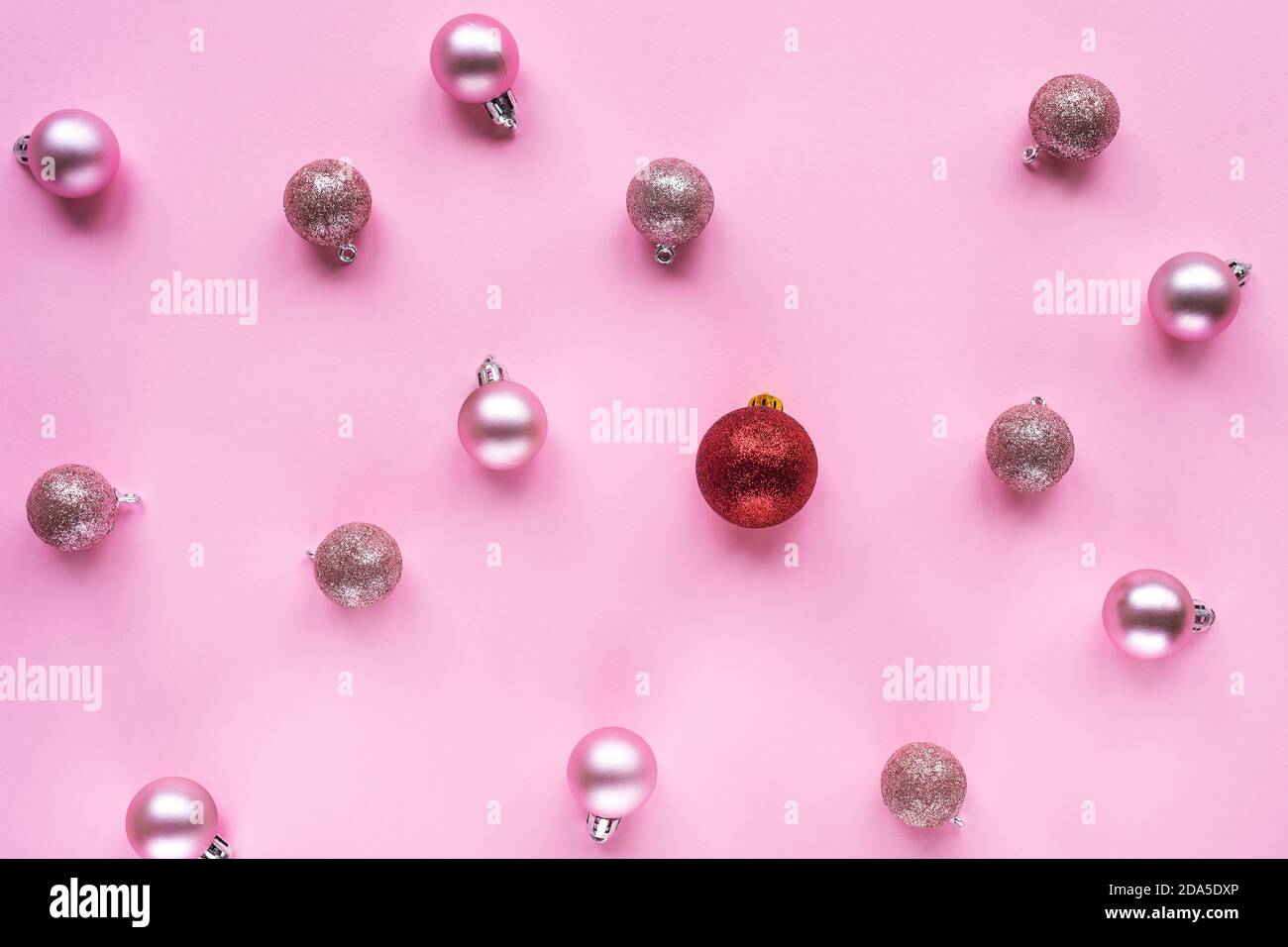 Une boule de noël rouge et beaucoup de boules roses sur la table. Concept de Noël ou de nouvel an. Différent, non standard. Vue de dessus Banque D'Images