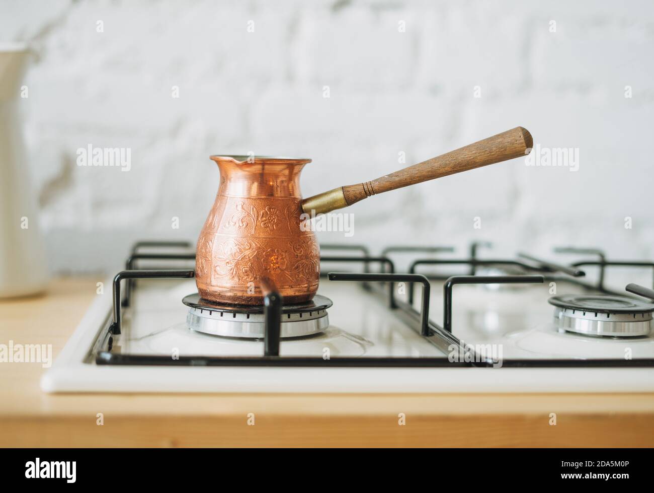Cafetière en cuivre sur la cuisinière dans la cuisine lumineuse, routine du matin Banque D'Images
