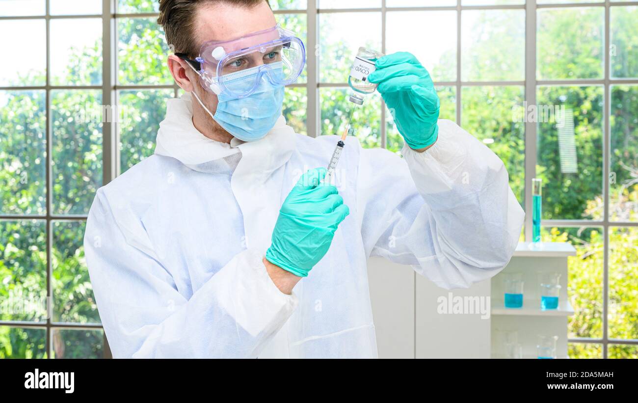 Un scientifique mâle portant une combinaison de protection contenant un vaccin contre le coronavirus et travaillant avec de nombreux équipements de laboratoire pour la recherche d'un vaccin en laboratoire. Rés. Médicale Banque D'Images