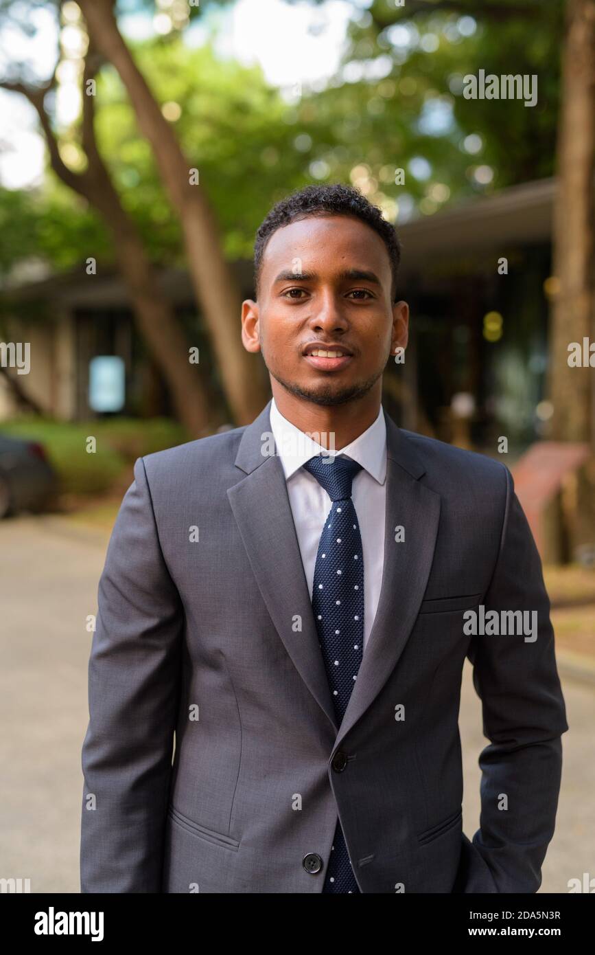 Portrait d'un jeune homme d'affaires africain souriant à l'extérieur Banque D'Images