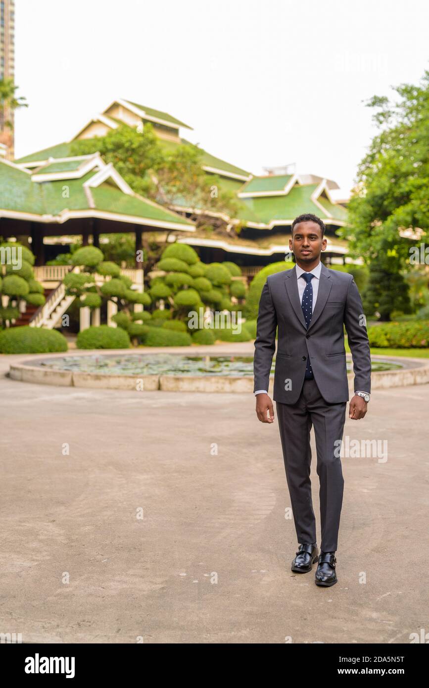 Portrait d'un jeune homme d'affaires africain charmant marchant à l'extérieur Banque D'Images