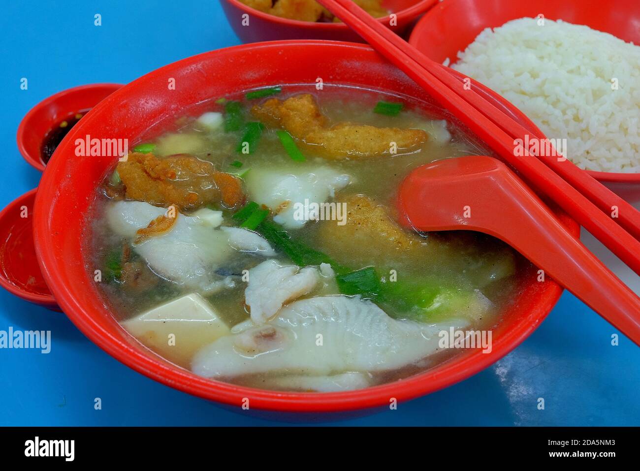 Un bol de soupe de poisson en tranches - un plat préféré de Singapour fait de poisson, de légumes et de caillé de haricots dans le bouillon, disponible dans les aires de restauration et les centres de vente au aubéole. Banque D'Images