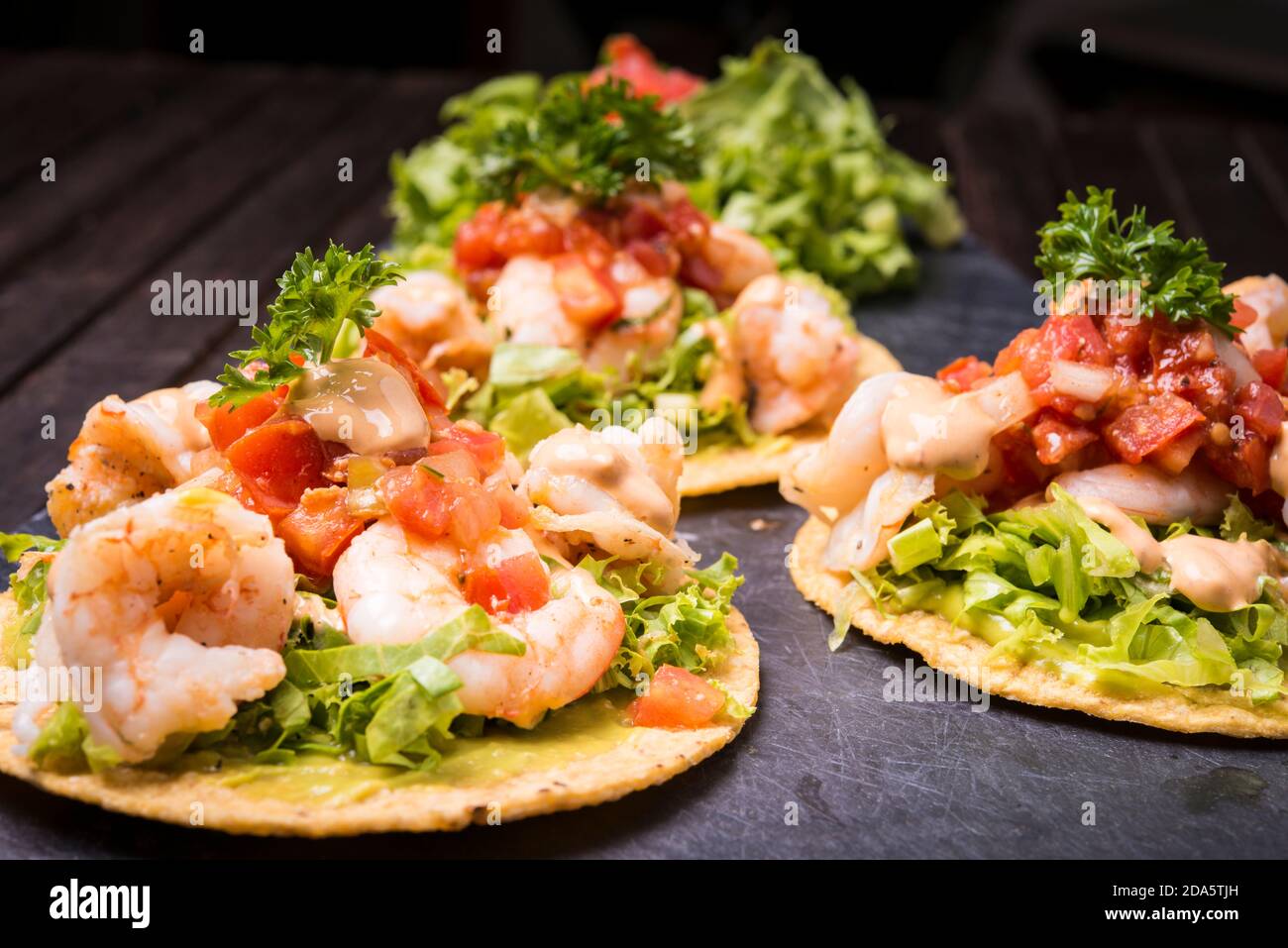 Tacos aux crevettes sur tortilla à coque dure avec garniture mexicaine arrière-plan en bois sombre Banque D'Images