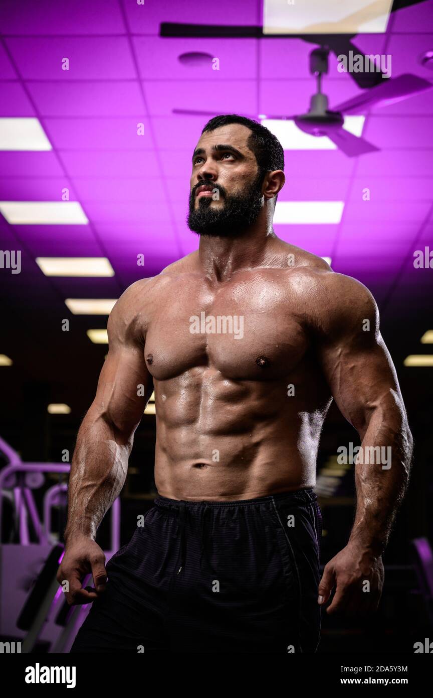 jeune homme fort barbu dans la salle de sport éclairé avec le violet léger Banque D'Images
