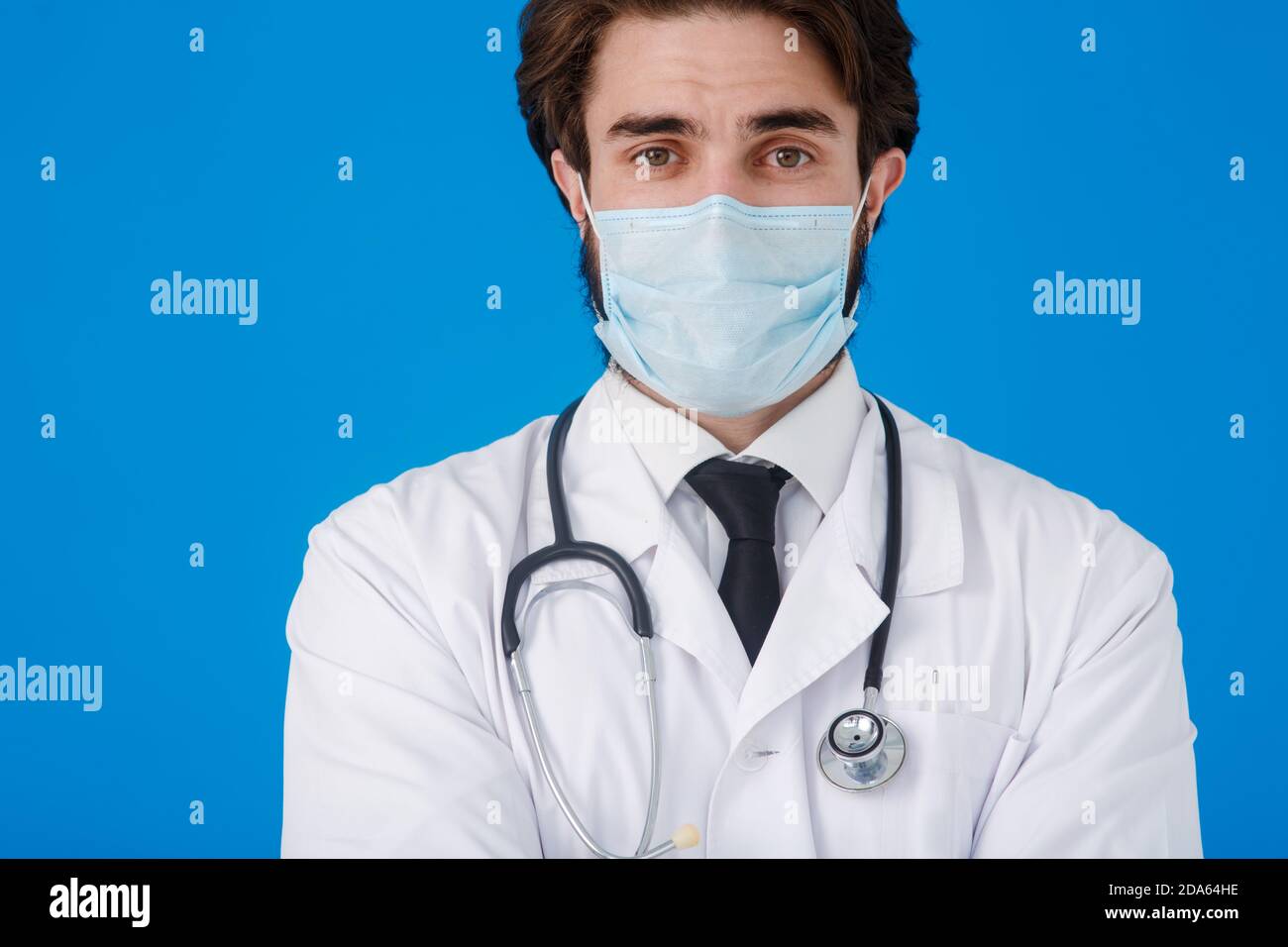 Médecin sous un manteau blanc et un masque médical, avec un endoscope autour de son cou de près - sur un fond bleu. Concept de protection contre les virus et Banque D'Images
