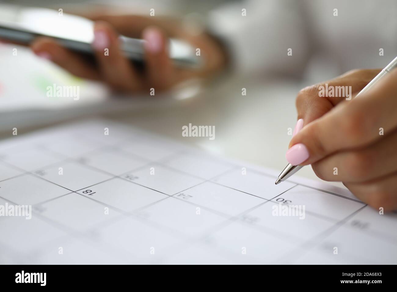 La main de la femme tient le stylo et le calendrier des marques. Banque D'Images