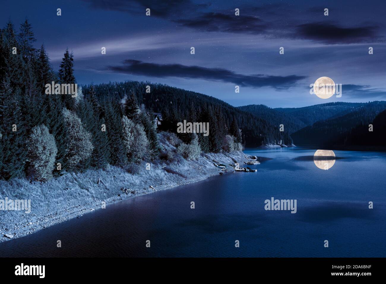 lac de montagne en automne la nuit. magnifique paysage de campagne en pleine lune. ciel bleu avec des nuages moelleux se reflétant sur la surface de l'eau Banque D'Images