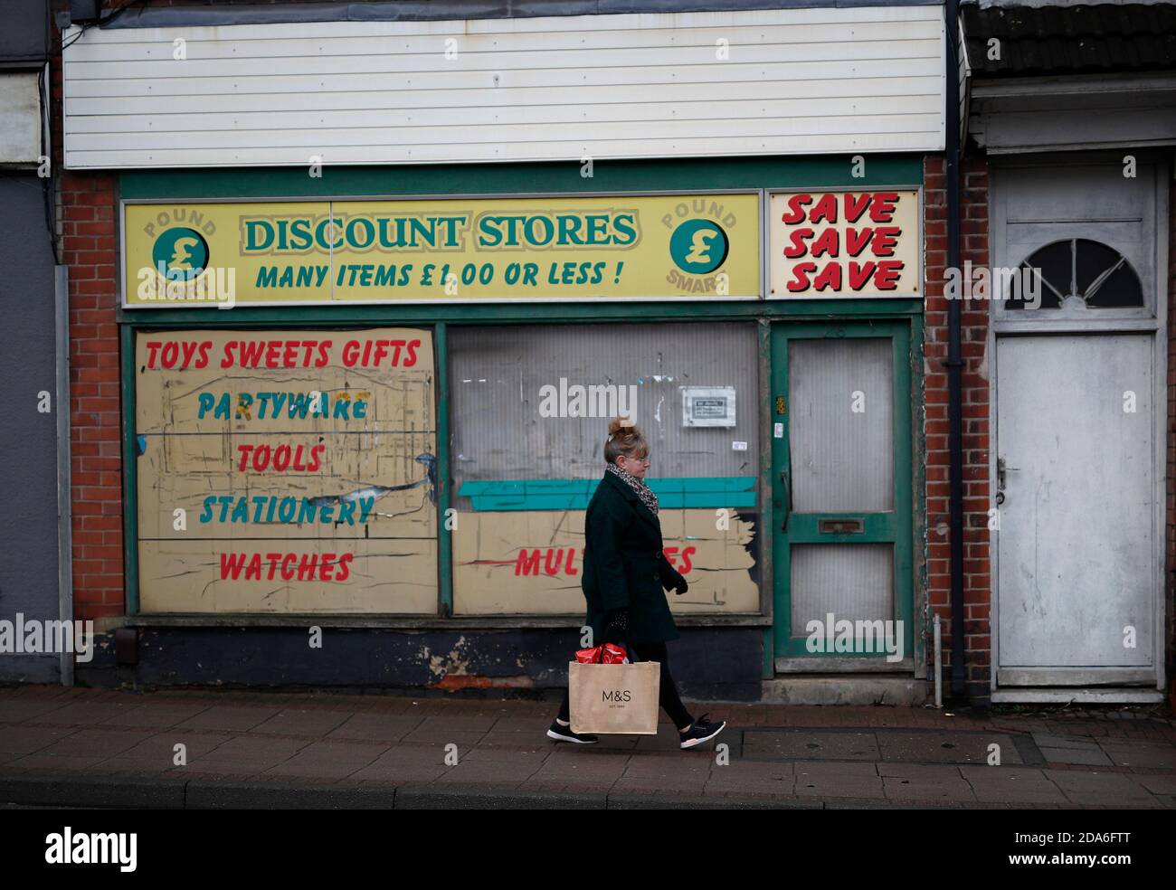 Coalville, Leicestershire, Royaume-Uni. 10 novembre 2020. Une femme passe devant un ancien magasin de rabais après que le taux de chômage au Royaume-Uni ait augmenté alors que le coronavirus continue de frapper le marché de l'emploi. Credit Darren Staples/Alay Live News. Banque D'Images