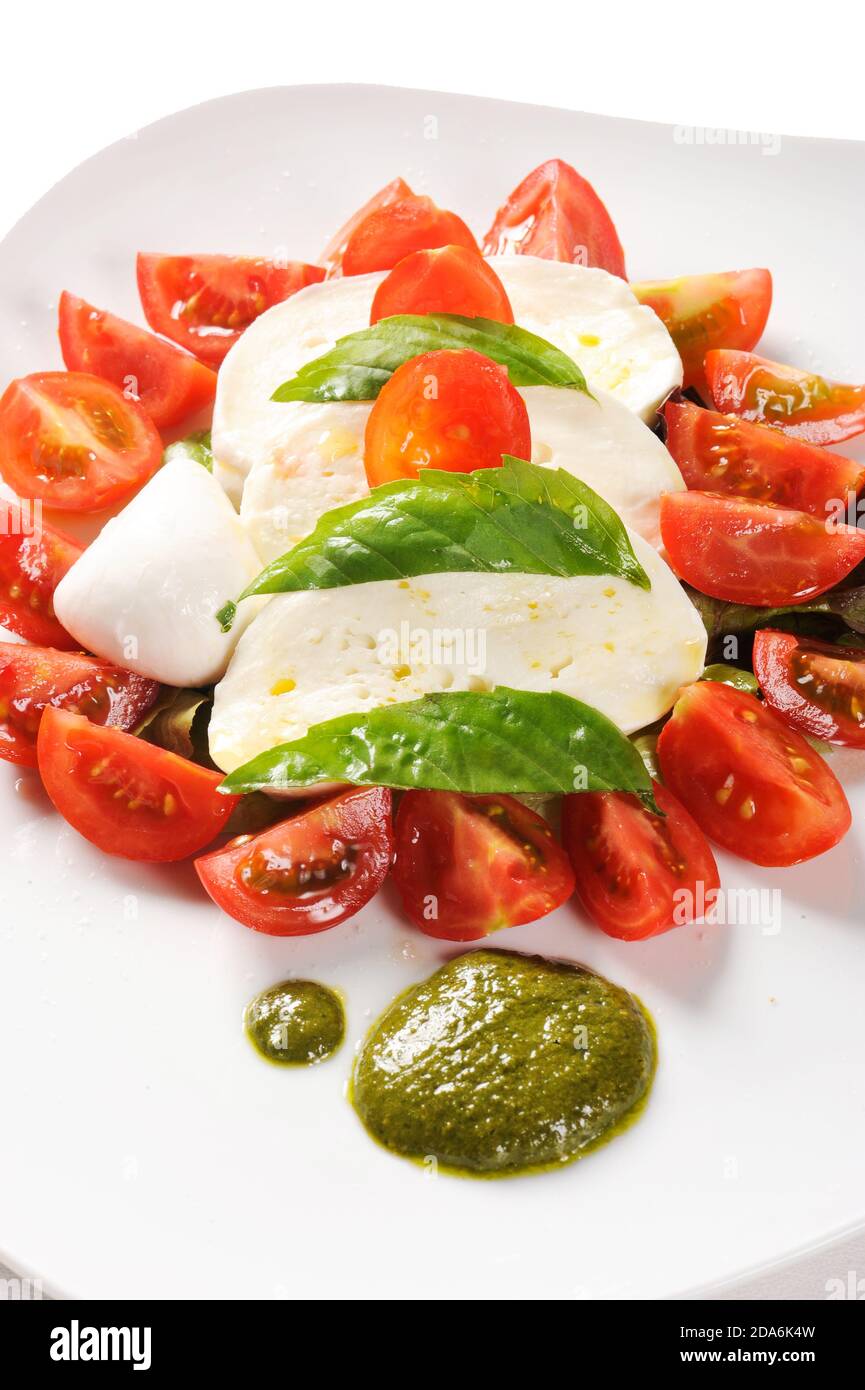 Plat typiquement italien de la région de Campanie mozzarella, tomates et pesto de basilic, appelé caprese sur fond blanc Banque D'Images