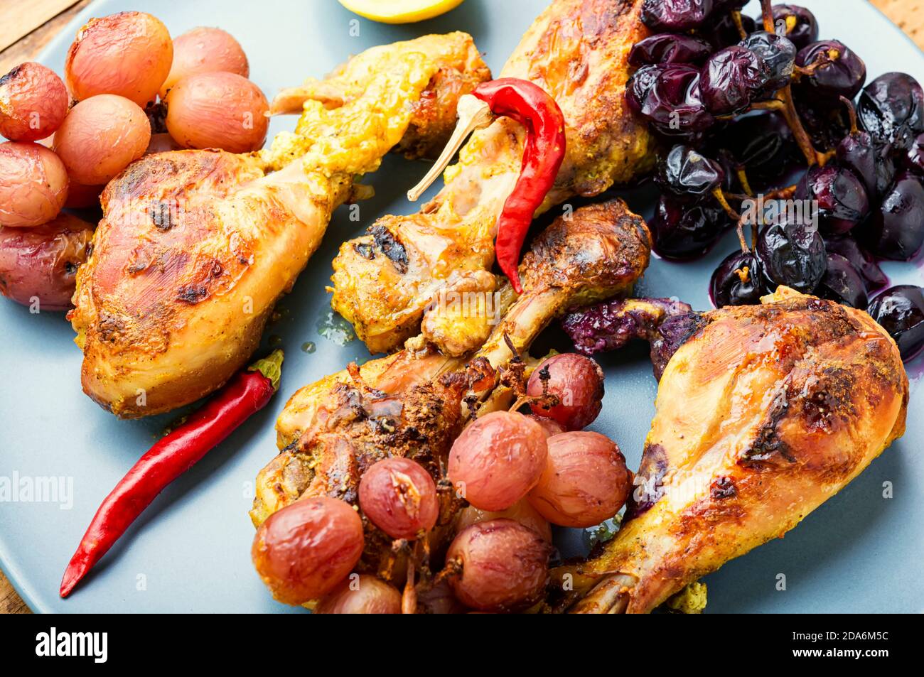 Cuisses de poulet cuites au four avec du raisin. Cuisses de poulet rôties sur l'assiette Banque D'Images