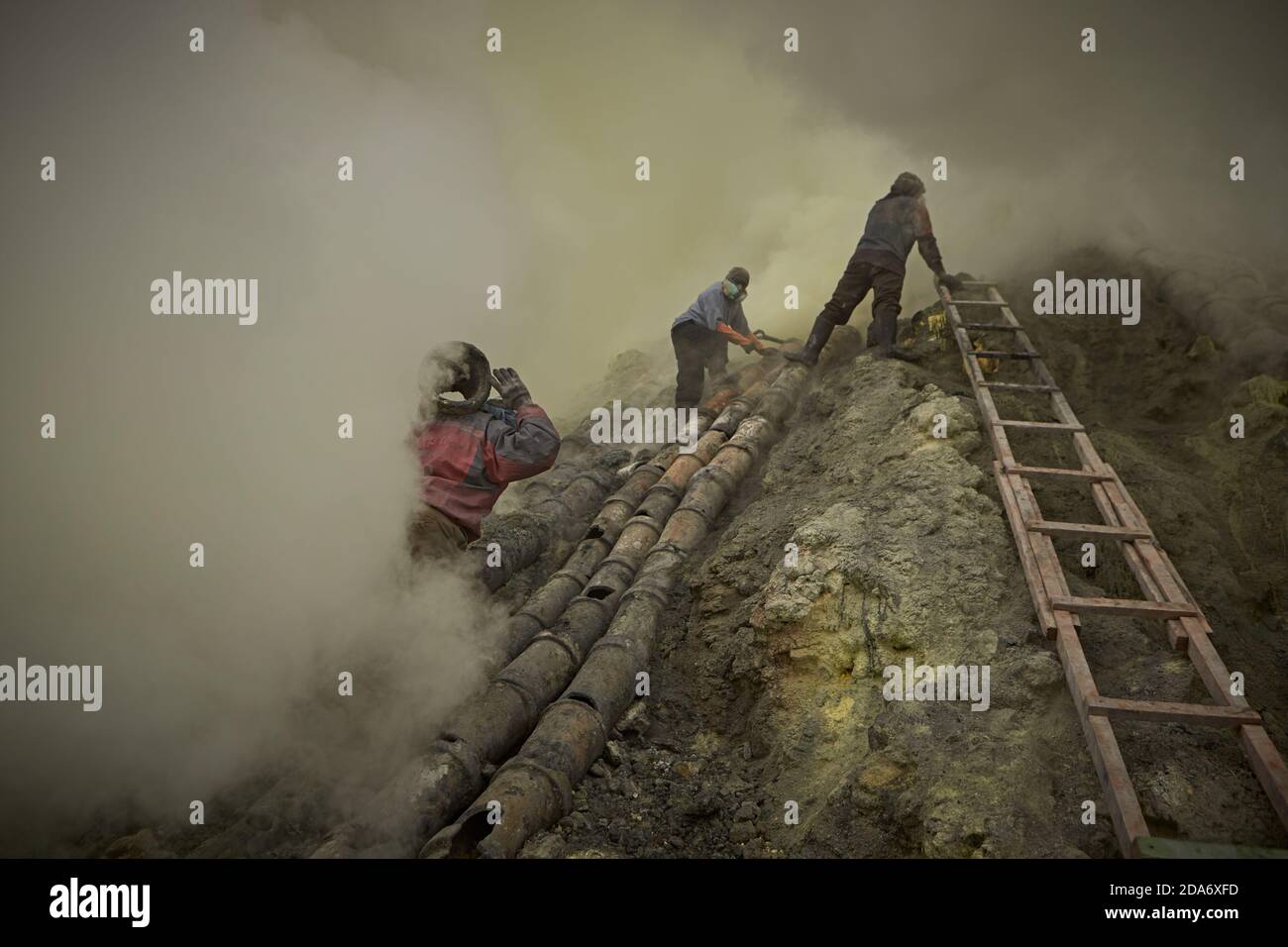 East Java, Indonésie, février 2016. Mineurs de soufre travaillant à la réparation de tuyaux pour l'extraction minérale dans le cratère du volcan actif Kawah Ije Banque D'Images