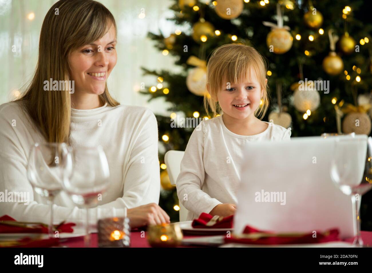 Une famille heureuse avec un enfant fête Noël avec ses amis lors d'un appel vidéo à l'aide d'une webcam. La veille de Noël, la famille accueille leurs parents Banque D'Images