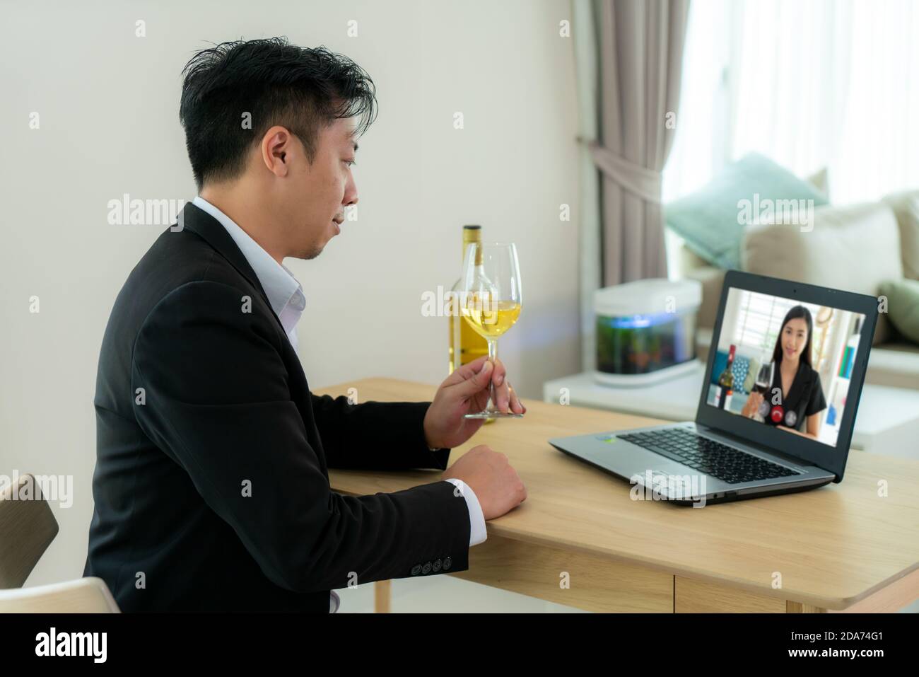 Un homme asiatique virtuel happy hour et boire du vin de raisin blanc en ligne avec son ami dans la vidéo conférence avec une tablette numérique pour un Banque D'Images