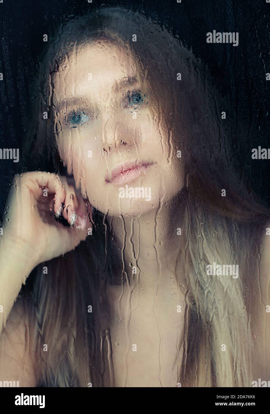 Portrait de jeune femme blonde derrière la vitre avec gouttes de pluie. Concept de verrouillage d'auto-isolation. Banque D'Images