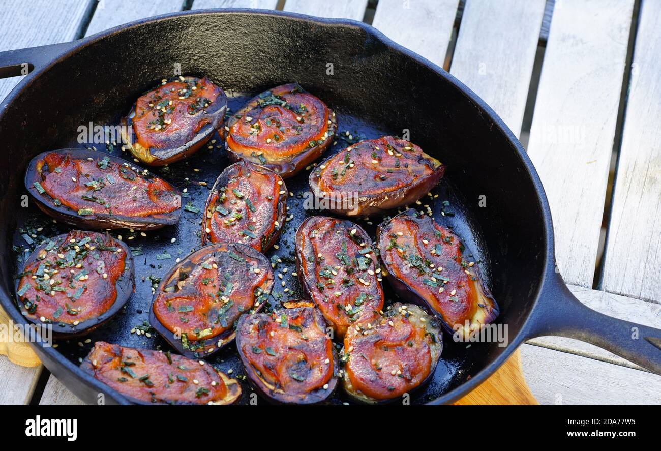 Plat d'aubergines grillées émaillées de miso avec graines de sésame une poêle en fonte Banque D'Images