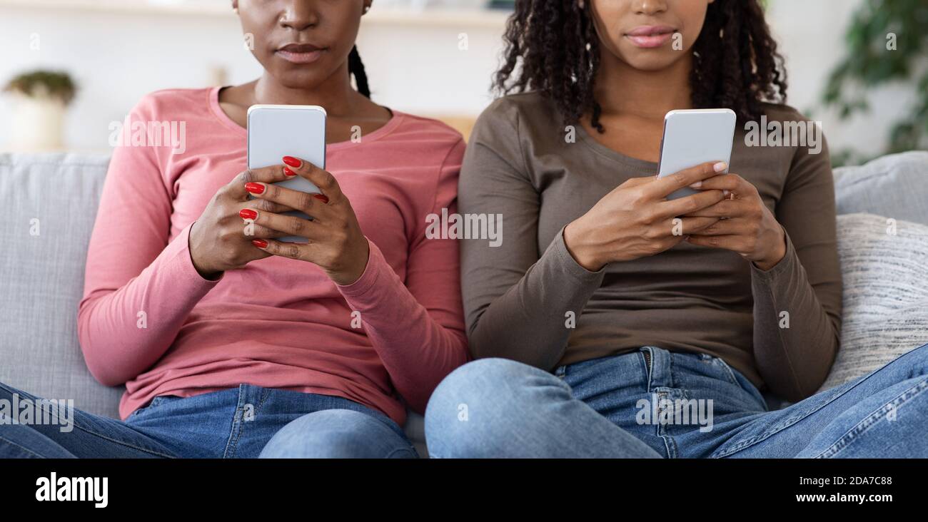 Femmes noires méconnues utilisant un téléphone portable à la maison Banque D'Images