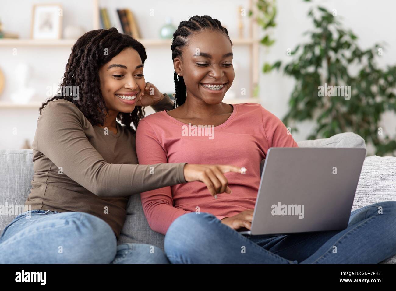 Des femmes noires heureuses utilisant un ordinateur portable à la maison, la navigation sur Internet Banque D'Images