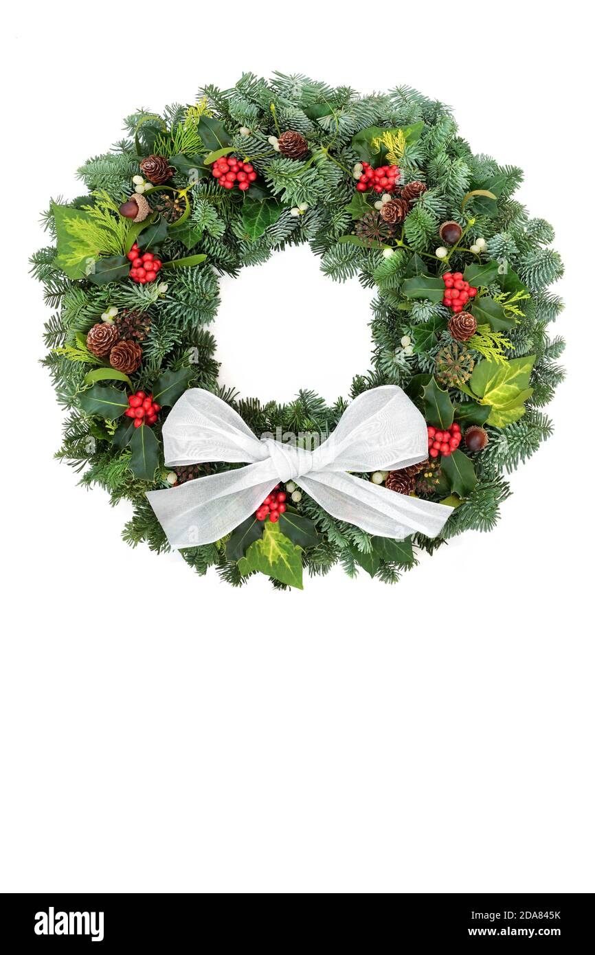 Couronne de Noël verte d'hiver naturelle avec sapin d'épicéa, houx, glands, cônes de pin et GUI sur fond blanc et noeud. Symbole traditionnel. Banque D'Images Couronne de Noël verte d'hiver naturelle avec sapin d'épicéa, houx, glands, cônes de pin et GUI sur fond blanc et noeud. Symbole traditionnel. Banque D'Images