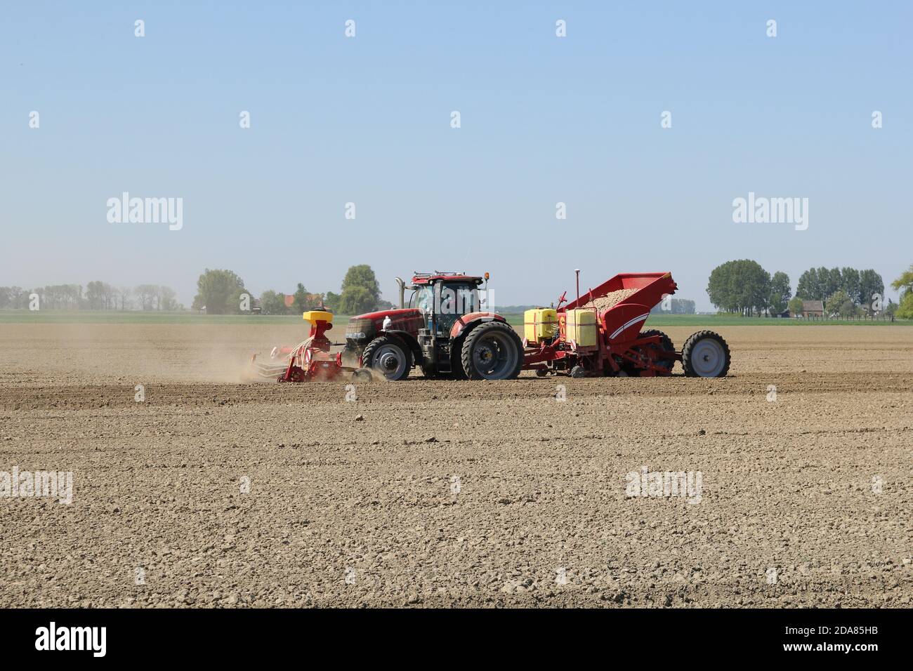 un tracteur équipé de machines plante des pommes de terre dans le champ de zeeland, aux pays-bas, à une période sèche au printemps Banque D'Images