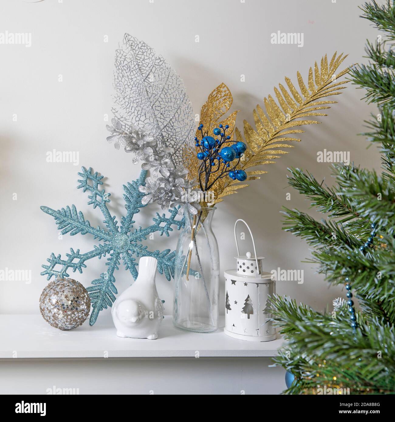 Décoration de Noël : flocon de neige bleu à paillettes artificielles, porte-bougie et porte-bougie en porcelaine blanc, figurine, bullfinch oiseau sur la console. Copier l'espace Banque D'Images