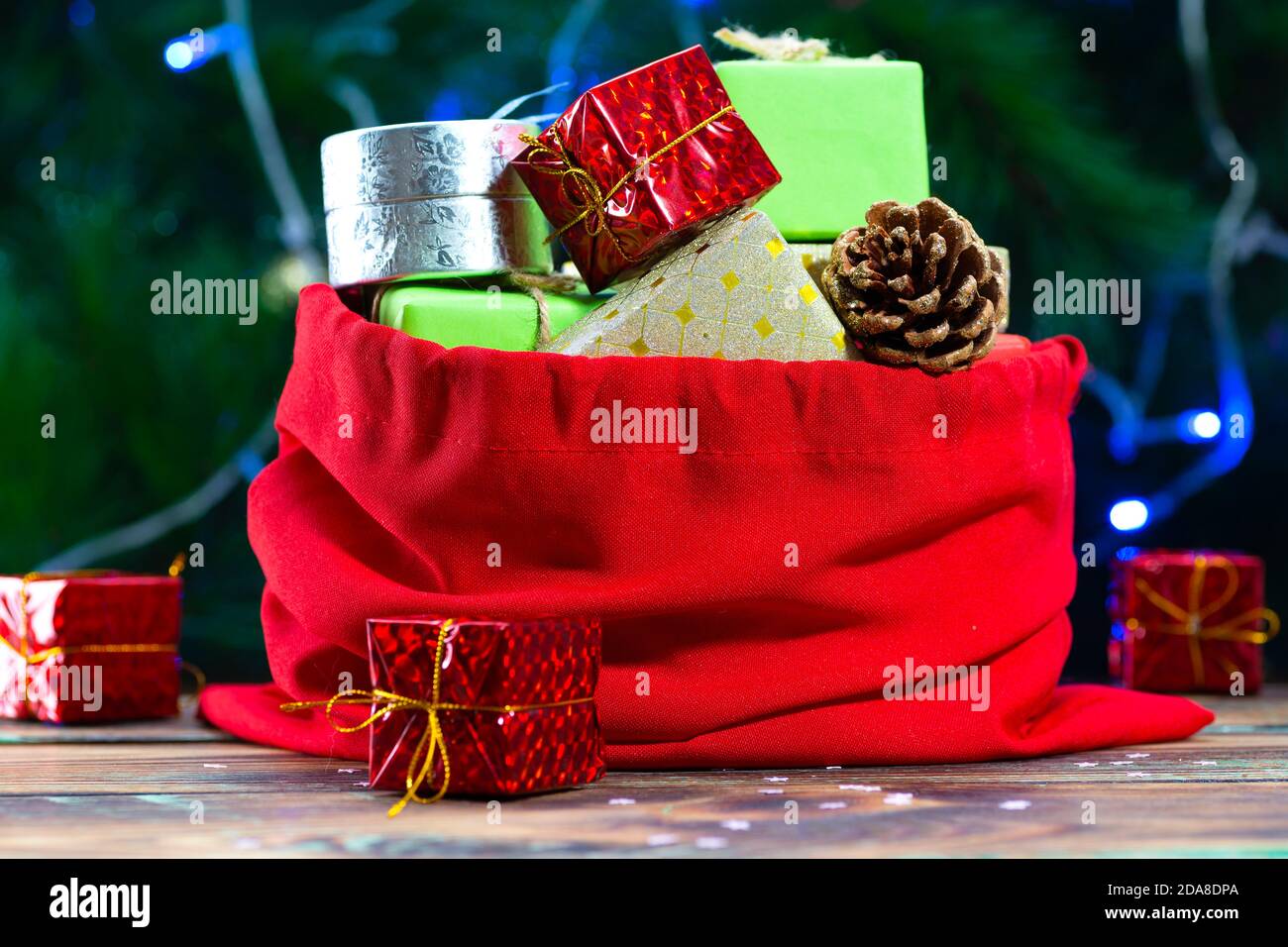 Sac du Père Noël avec cadeaux sur une table en bois contre Le fond d'un arbre de Noël décoré Banque D'Images