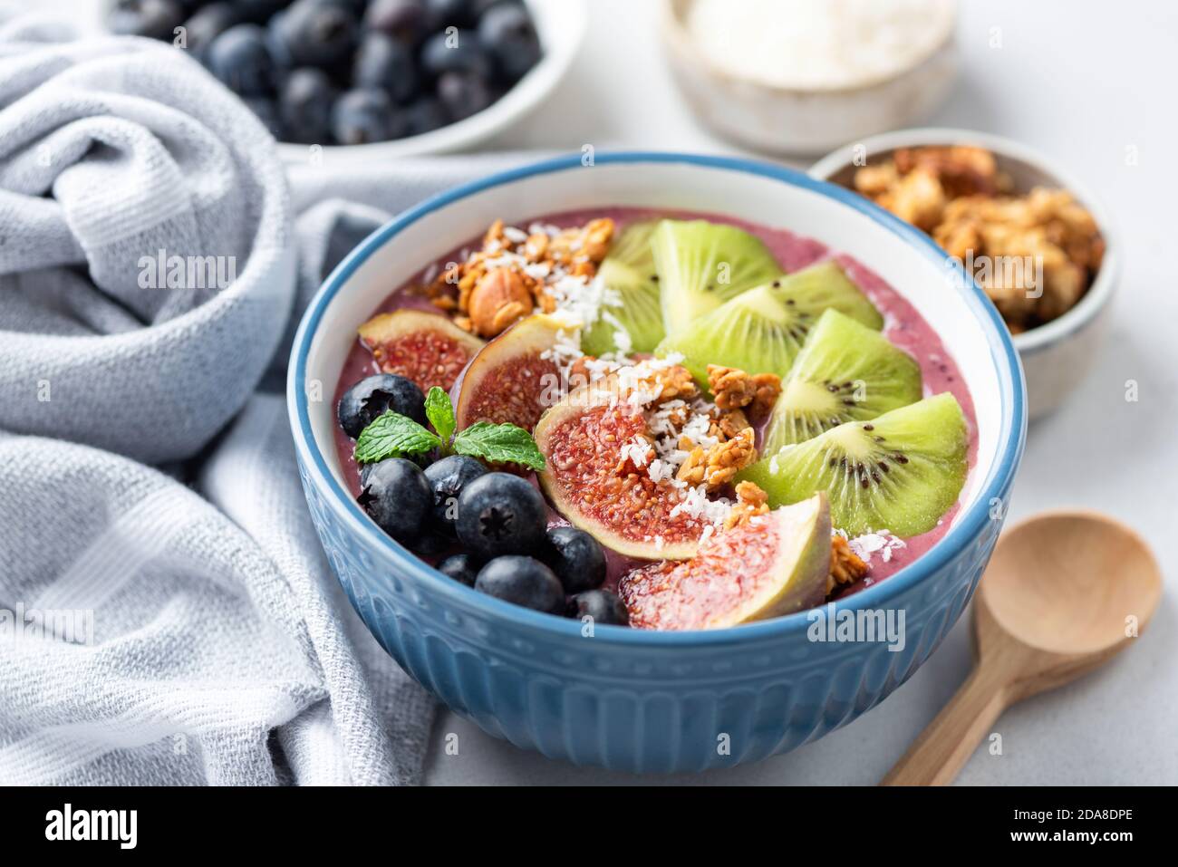 Bol de smoothie aux fruits Superfood avec kiwi, figues, granola, myrtilles et noix de coco. Vue en gros plan Banque D'Images
