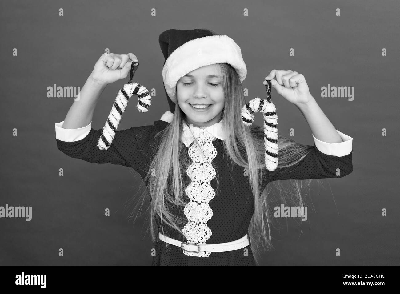 Meilleur décor de Noël. Happy kid tenir des cannes de bonbon. Petite fille aux décorations de Noël. Canne de noël ornement de Noël. Le rouge et le blanc des cannes de bonbon. Canne de Noël design. Décoration Nouvel an. Banque D'Images