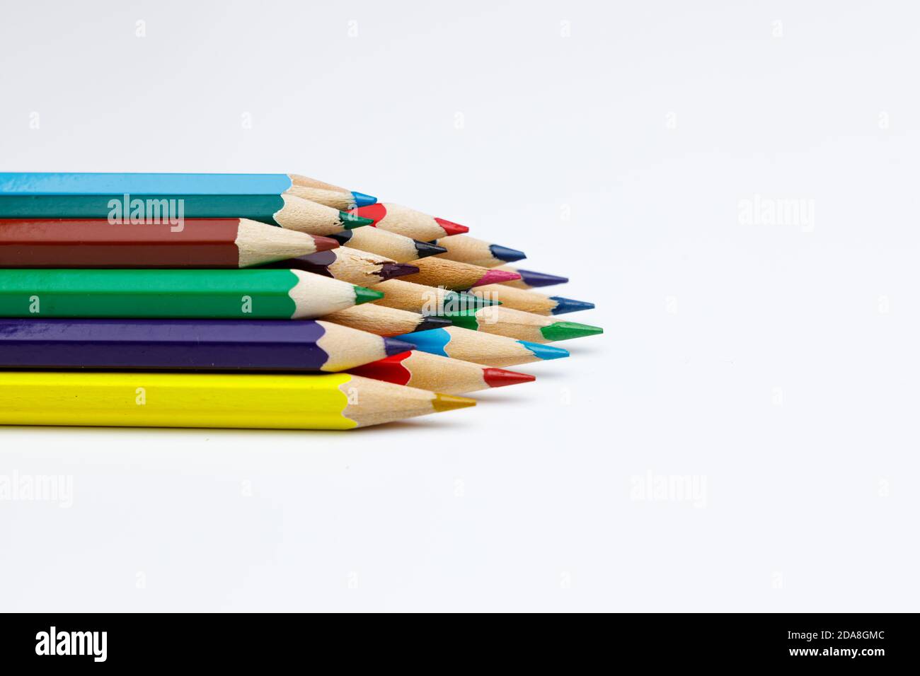 Vue latérale des crayons de couleur empilés avec de l'espace sur fond blanc uniforme, utilisation pour les présentations powerpoint ou les sites Web, les crayons pointent vers Banque D'Images