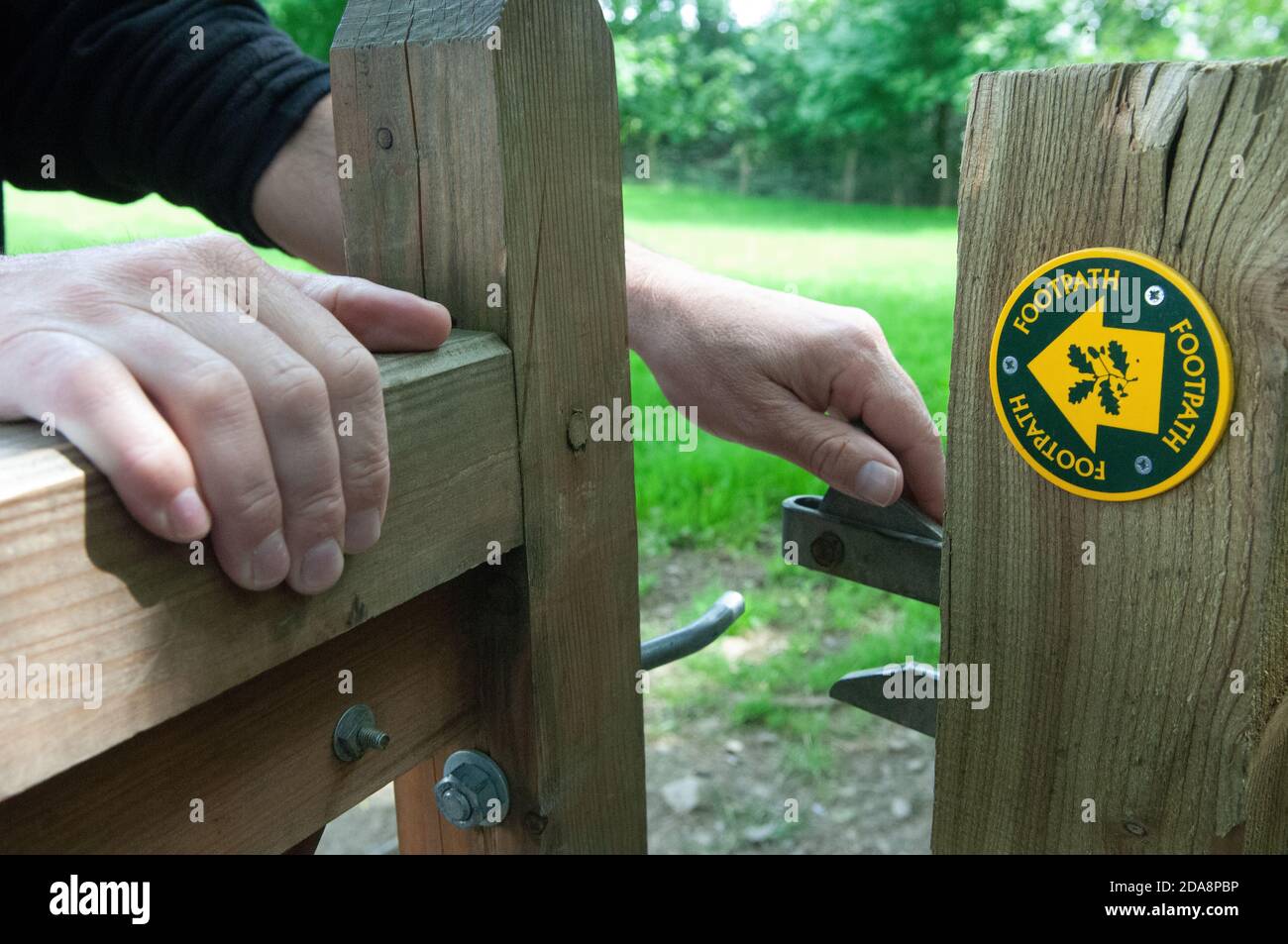 Mains ouvrant une barrière de sentier. Banque D'Images