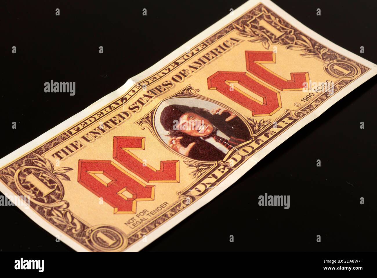 Faux billet de 1 dollar américain avec le visage des souvenirs du groupe de rock Angus Young AC/DC de 1990 sur fond noir Banque D'Images