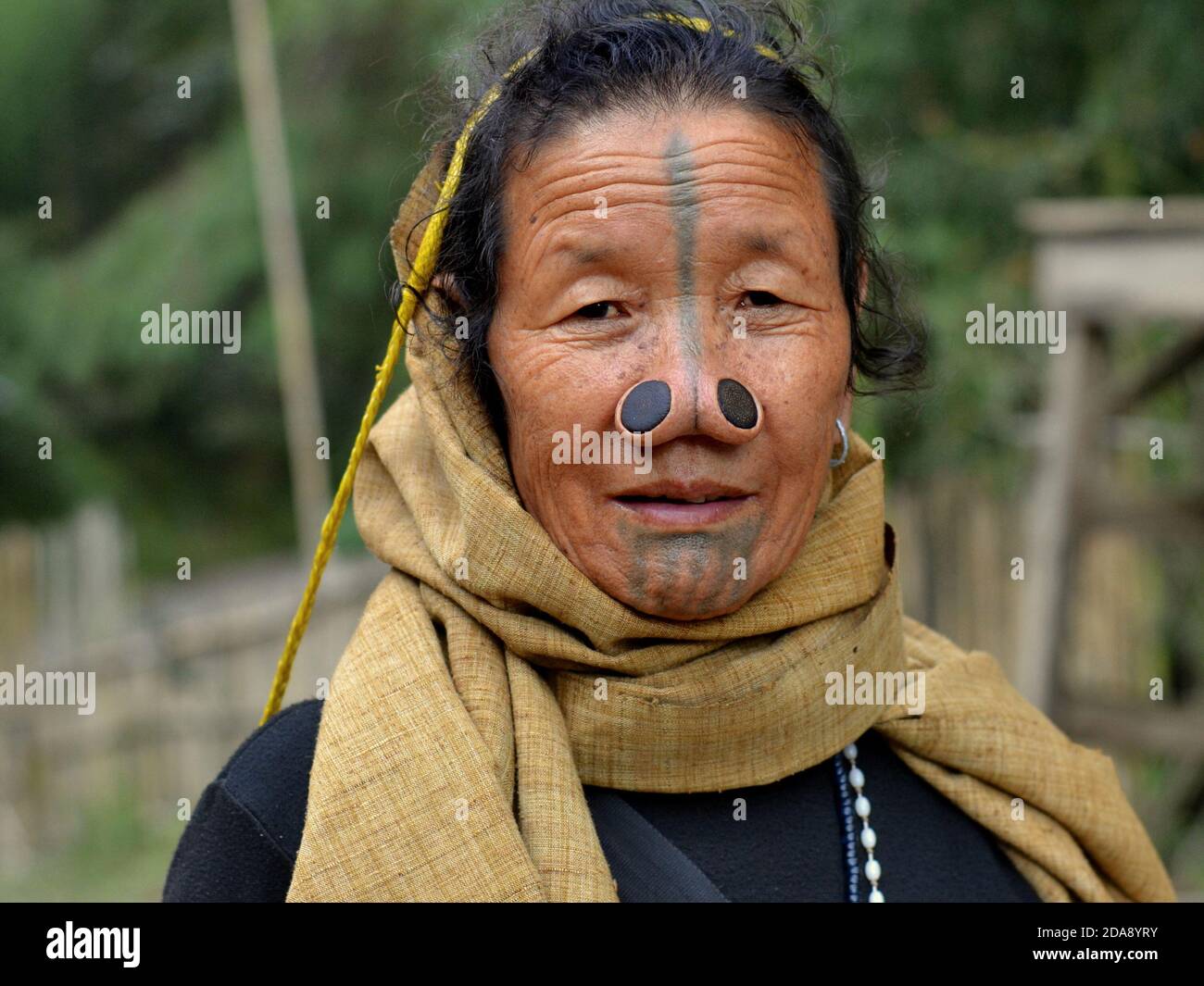 Femme tribale indienne du nord-est des Apatani âgée, avec des bouchons de nez en bois noir et des tatouages traditionnels pour le visage poses pour la caméra. Banque D'Images