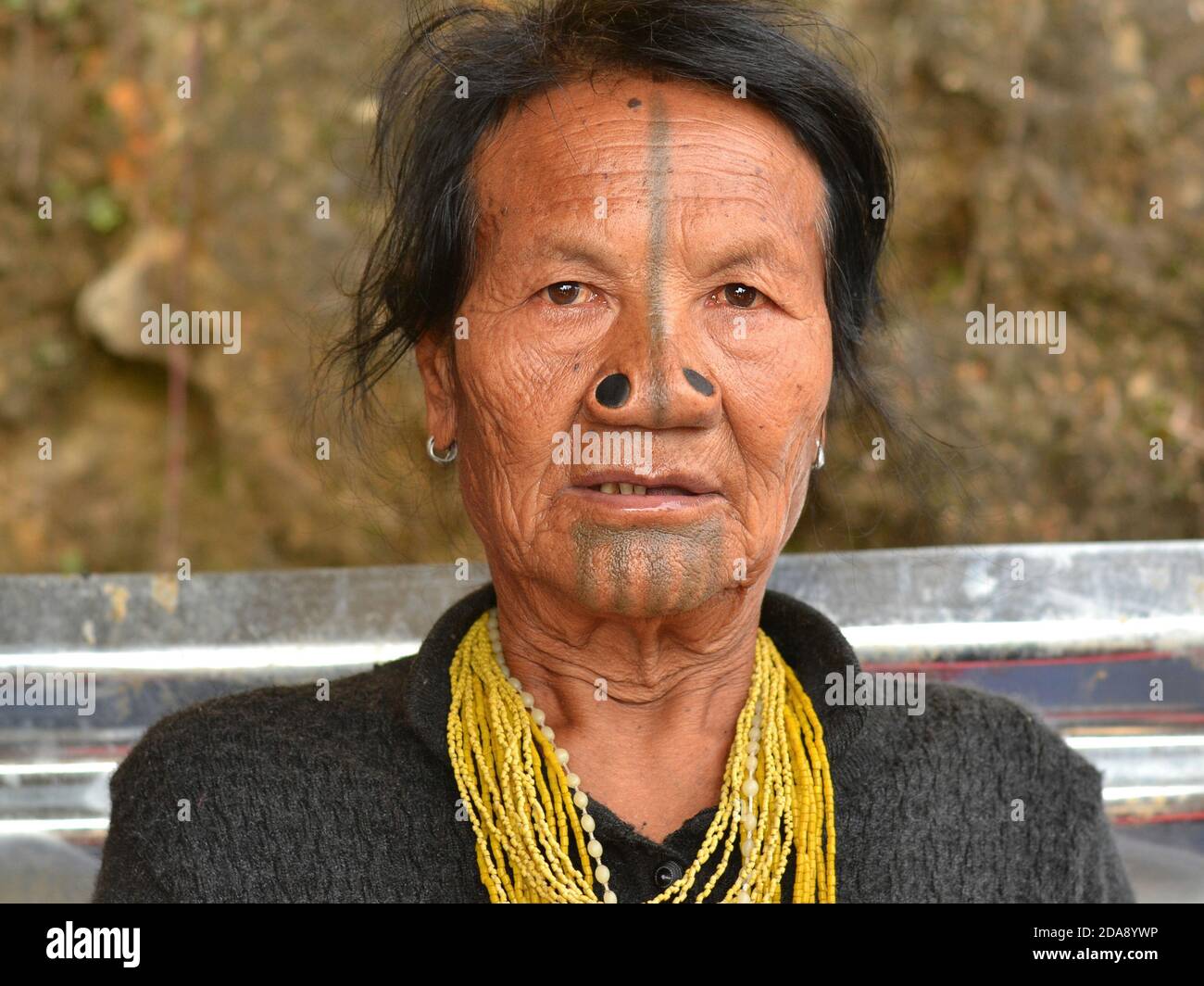 Femme tribale indienne du nord-est des Apatani âgée, avec des bouchons de nez en bois noir et des tatouages traditionnels pour le visage poses pour la caméra. Banque D'Images