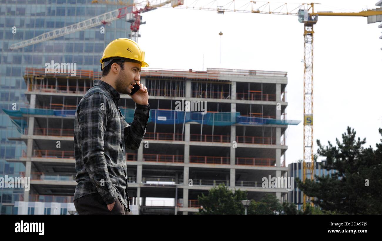Un ingénieur dans un casque de protection marche et parle sur le téléphone à Banque D'Images