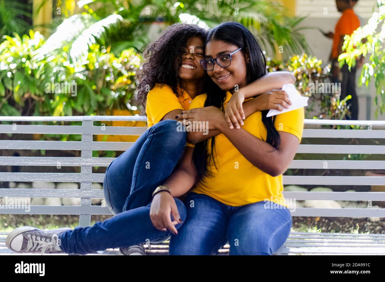 deux femmes noires de 20-25 ans avec des cheveux bouclés heureux dans le parc, assis sur un banc Banque D'Images