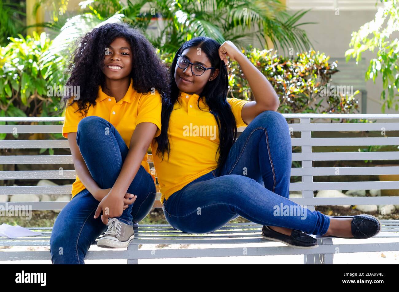 deux femmes noires de 20-25 ans avec des cheveux bouclés heureux dans le parc, assis sur un banc Banque D'Images