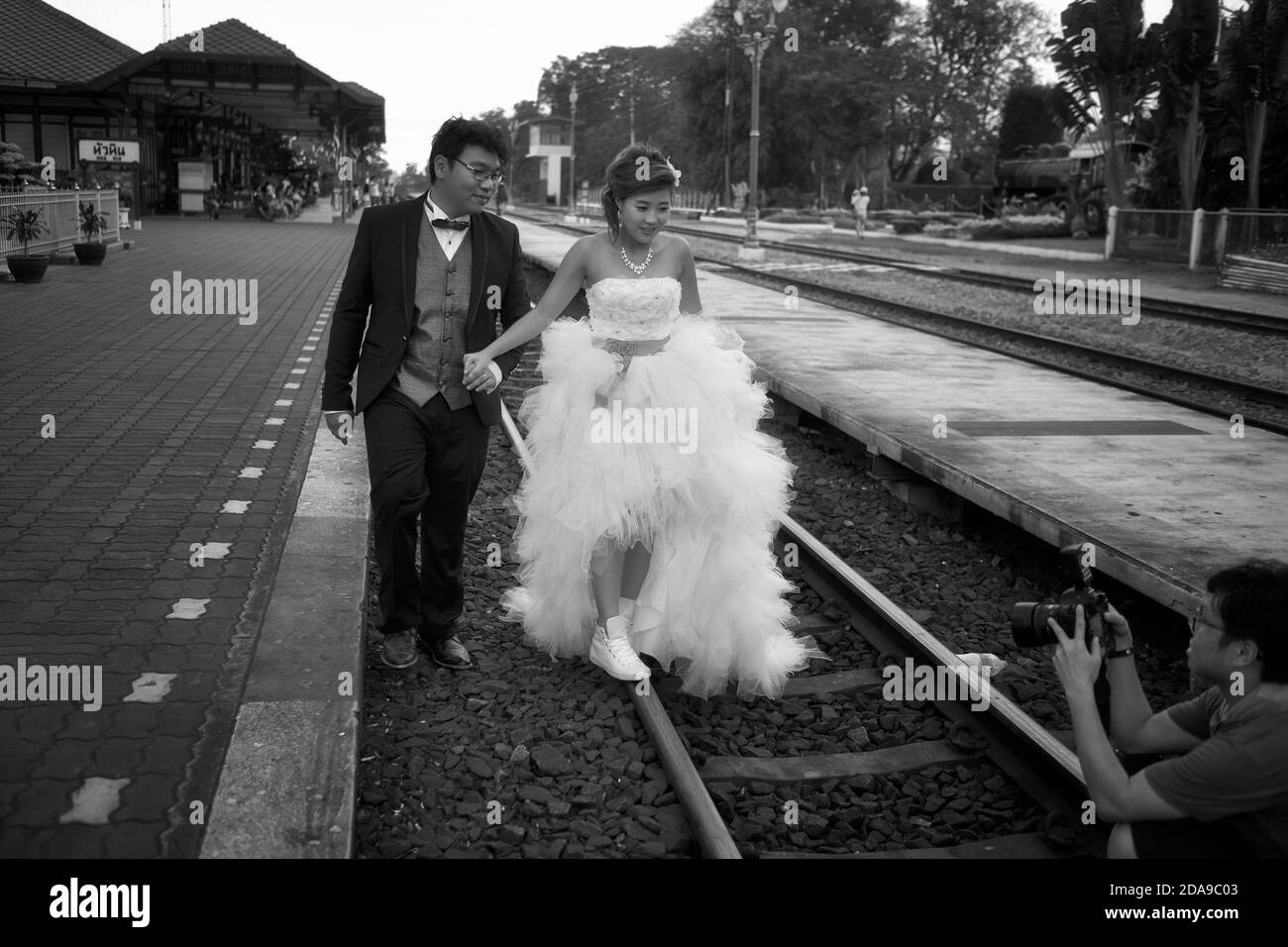 Emplacement inhabituel pour une séance photo avant mariage avec future mariée et marié sur la voie ferrée à une gare. Hua Hin Thaïlande. Noir et blanc Banque D'Images
