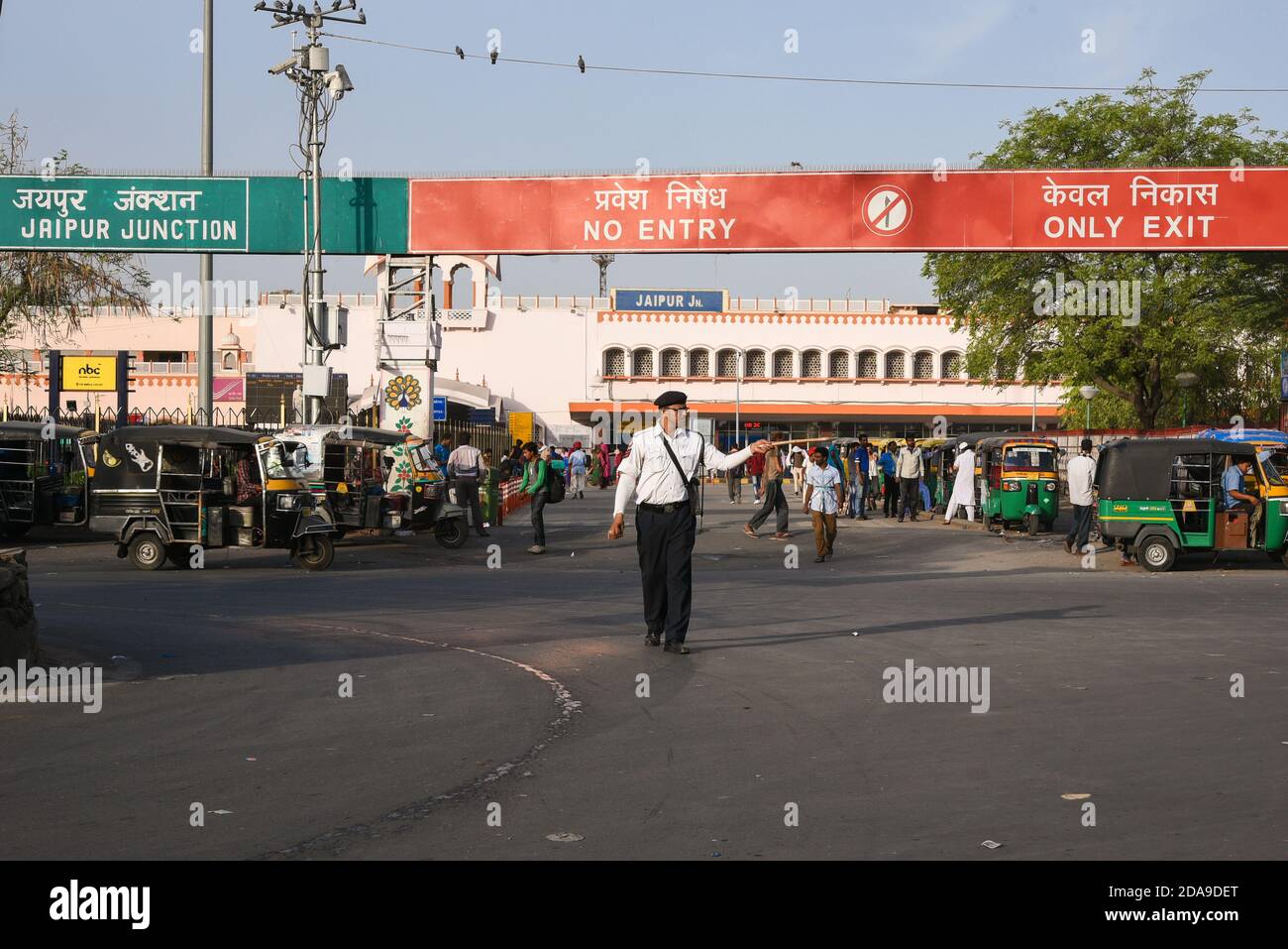 Police de la circulation contrôlant les véhicules sur la route. Passagers, navetteurs et véhicules à l'extérieur de la gare de Jaipur. Rajasthan, Inde du Nord. Banque D'Images