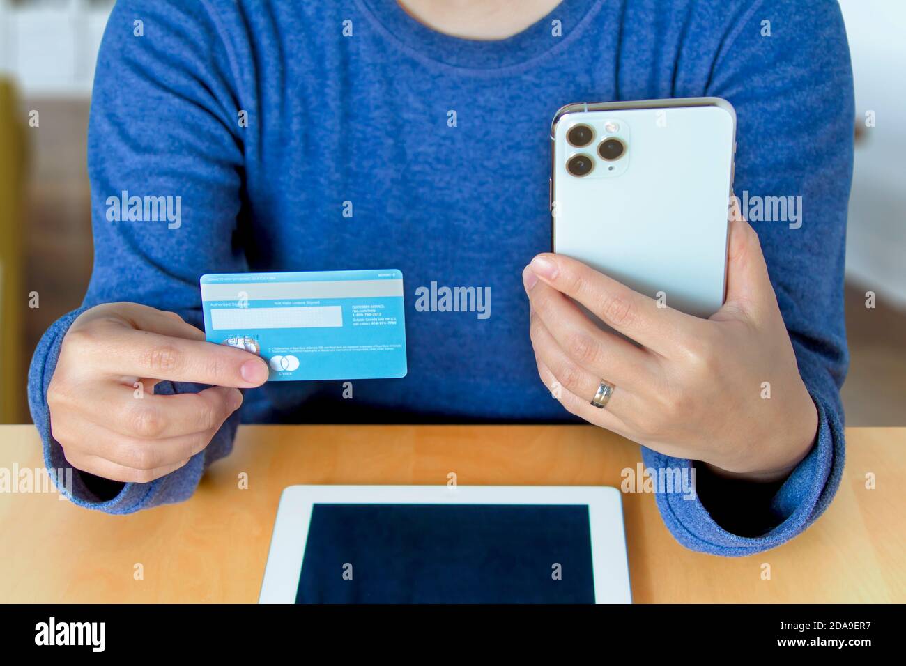Calgary Alberta, Canada. 10 novembre 2020. Une personne magasiner en ligne avec une carte de crédit Master Card et un iPhone assis sur une table avec et un iPad. Banque D'Images