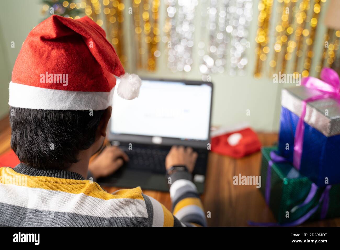Photo d'un jeune homme qui travaille sur un ordinateur portable avec Chapeau de père Noël à Noël ou la veille du nouvel an - concept de travail à la maison pendant la période des fêtes Banque D'Images