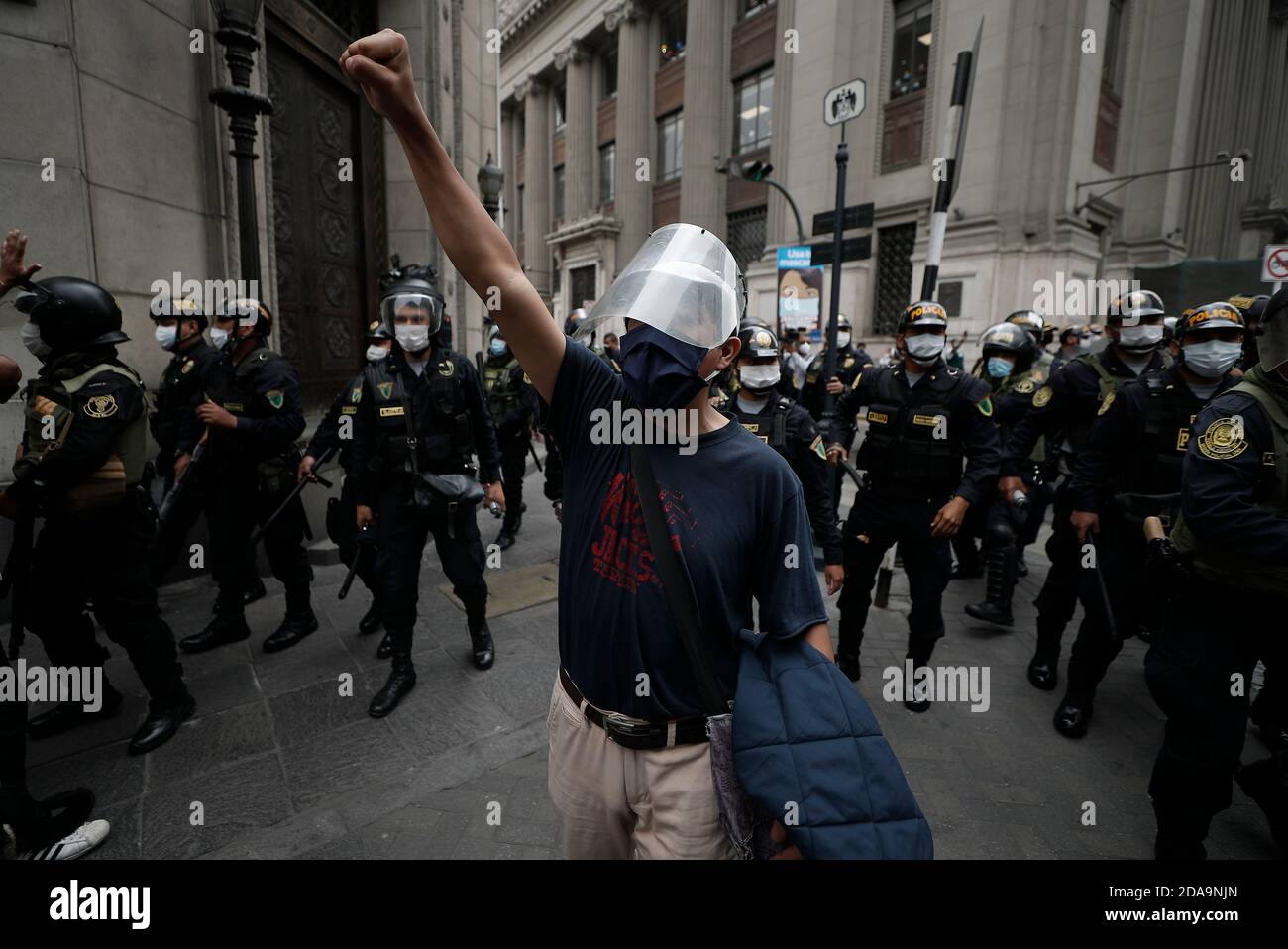 Lima, Pérou. 10 novembre 2020. Un homme proteste avec un poing levé contre la destitution, tandis que de nombreuses forces de police se tiennent autour de lui. Des milliers de personnes sont descendues dans les rues de la capitale péruvienne pour protester contre la déposition du président Martín Vizcarra. La crise politique secoue le Pérou, tandis que le pays est gravement touché par la pandémie de Corona et l'instabilité continue. Crédit : Alex Rosemberg/dpa/Alay Live News Banque D'Images