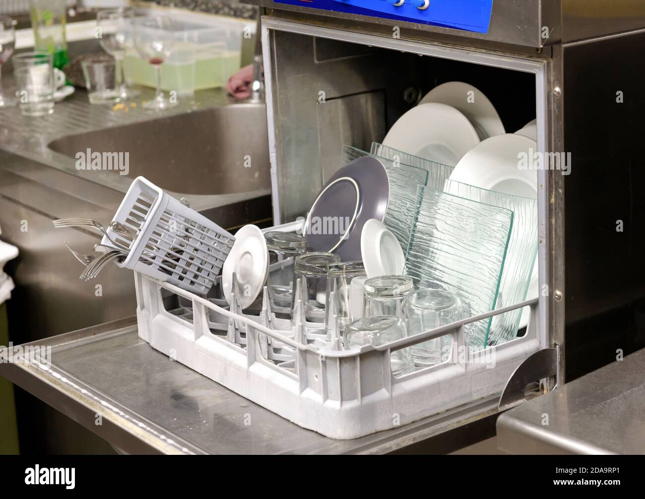 Ouvrez le lave-vaisselle rempli de vaisselle propre et de verres dans un petite cuisine de restaurant en gros plan sur la machine Banque D'Images