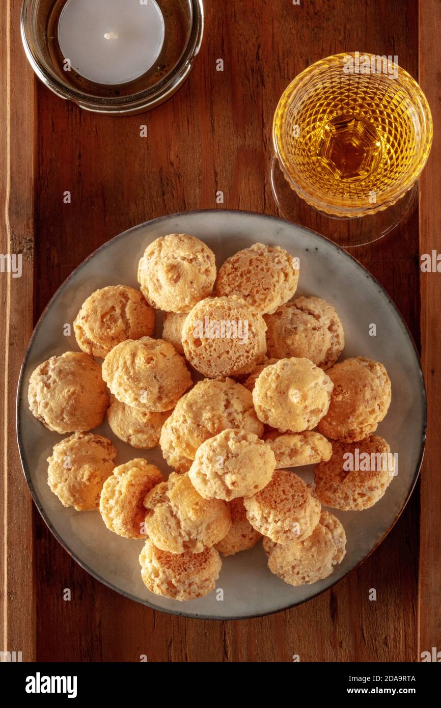 Amaretti, biscuits traditionnels aux amandes italiennes, avec un verre de liqueur Amaretto et une bougie, tiré d'en haut sur un fond en bois Banque D'Images