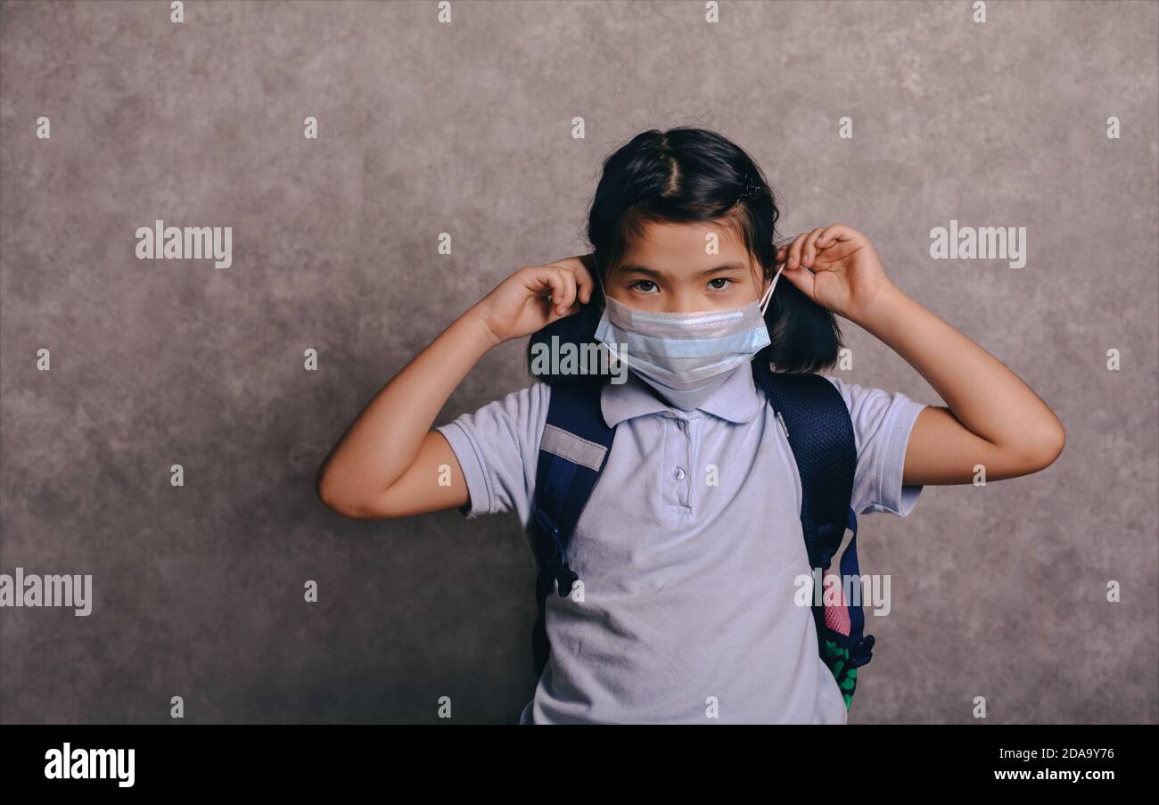 École primaire fille avec masque de visage de retour à l'école après la quarantaine et le verrouillage Covid-19. Enfant dans les masques Banque D'Images