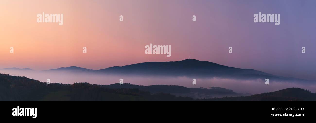 Paysage brumeux au coucher du soleil, montagnes qui s'élèvent des nuages de brouillard en arrière-plan, ciel clair - montagne Klet, République Tchèque Banque D'Images