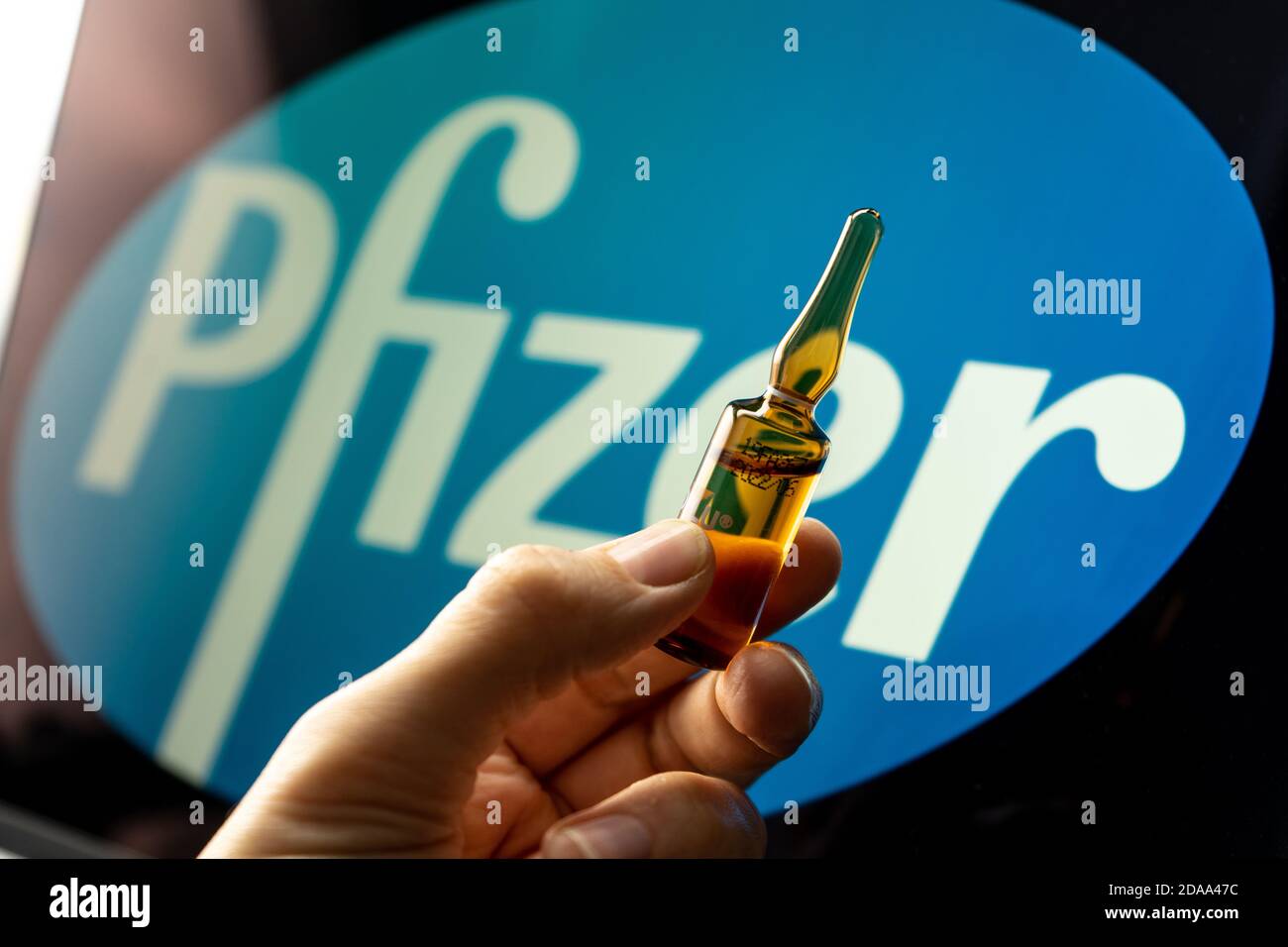 Société pharmaceutique Pfizer de vaccins contre le coronavirus. Logo Pfizer avec vaccin à main. Banque D'Images