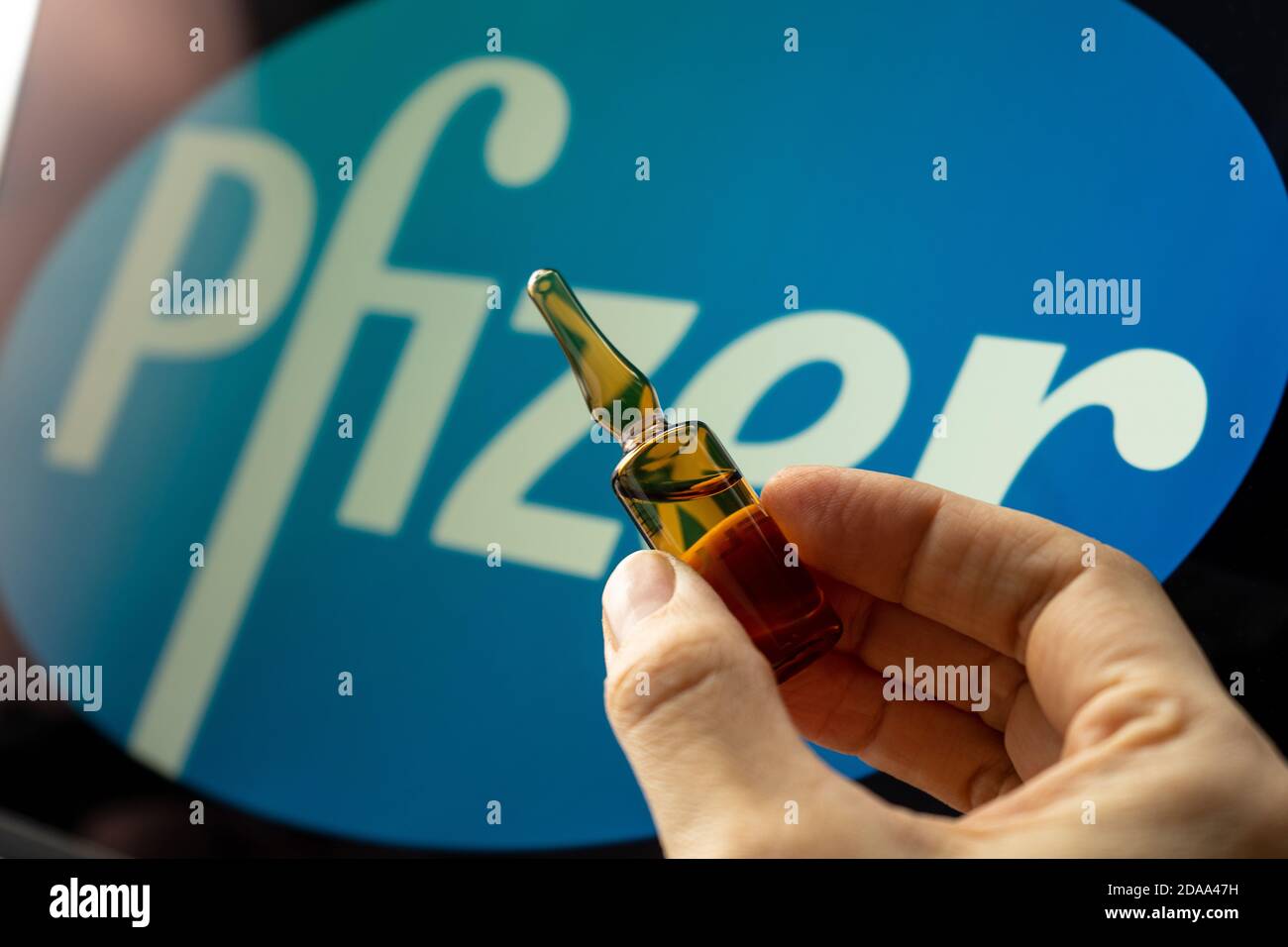 Société pharmaceutique Pfizer de vaccins contre le coronavirus. Logo Pfizer avec vaccin à main. Banque D'Images