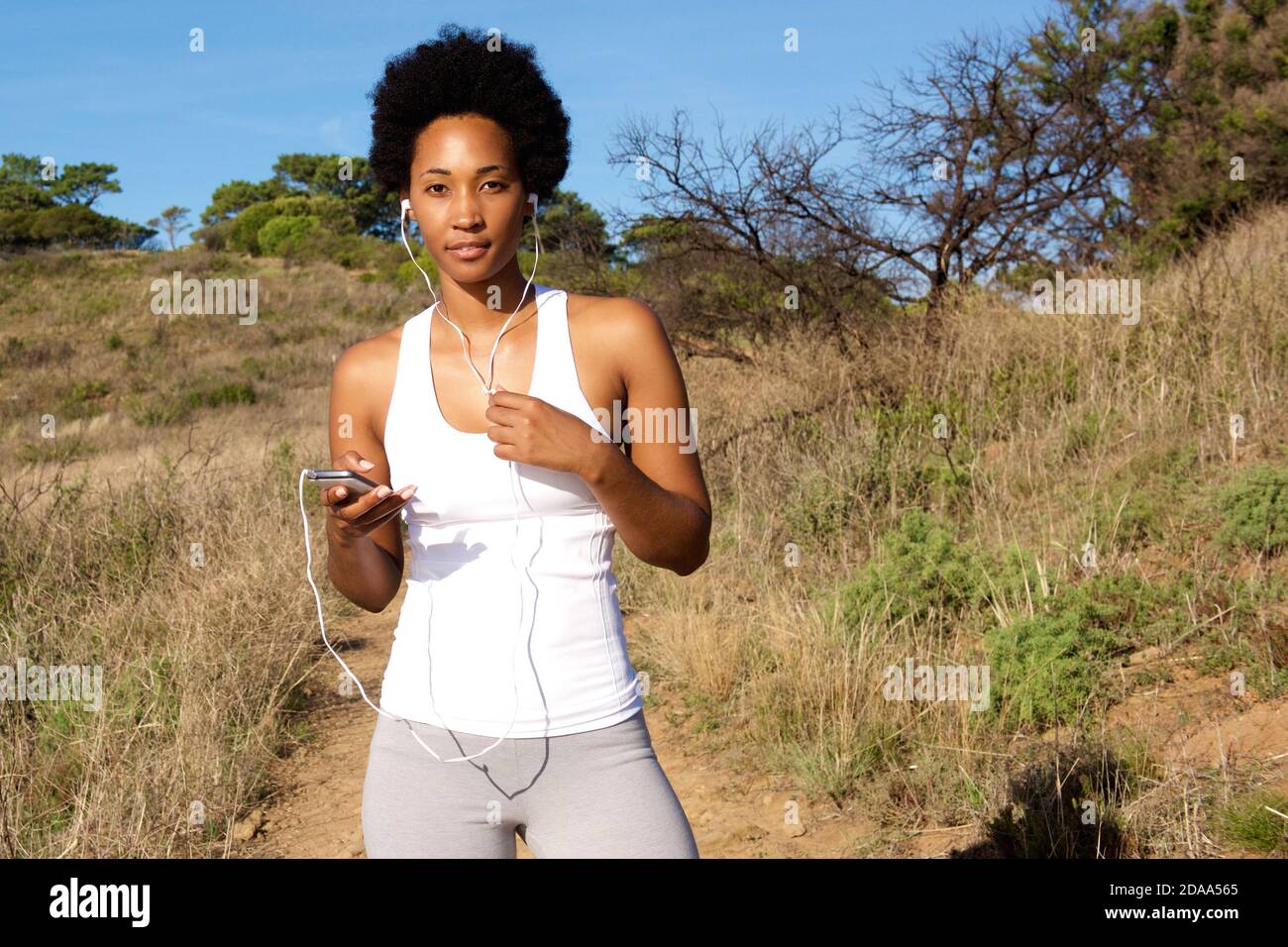 Portrait d'une jeune femme en bonne santé qui a la pause et l'écoute pour écouter de la musique pendant la course à l'extérieur Banque D'Images